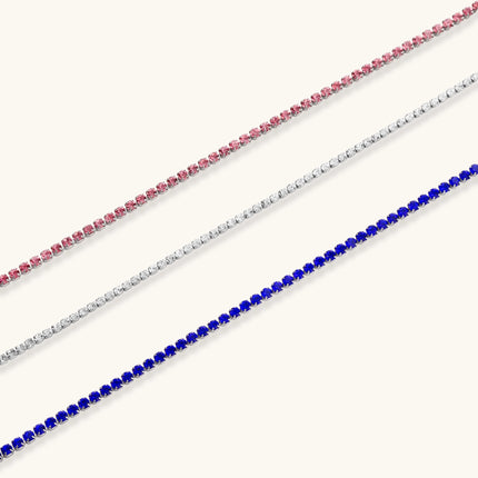 Pink zircon tennis bracelet with silver-tone stainless steel setting and lobster clasp extender chain, flat lay.