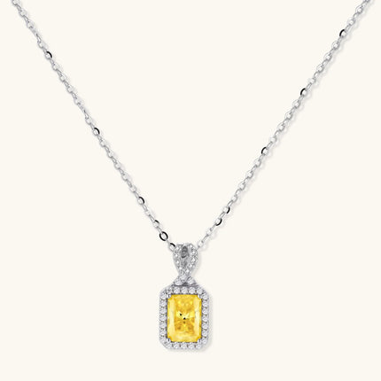 Yellow moissanite jewelry set with emerald-cut stones in sterling silver halo settings on white background.