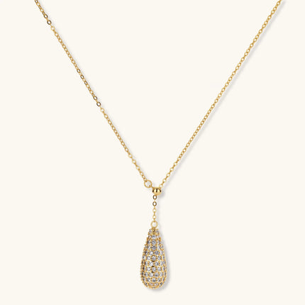 Gold-plated teardrop necklace and earrings covered in AAA cubic zirconia crystals on cream background.