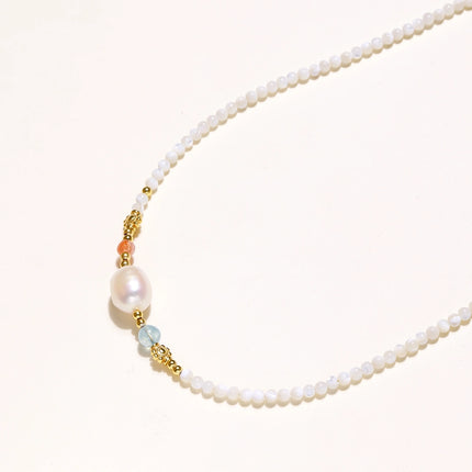 Beaded necklace with small white moonstone beads, central baroque freshwater pearl, coral and blue stone accents, gold floral spacers.