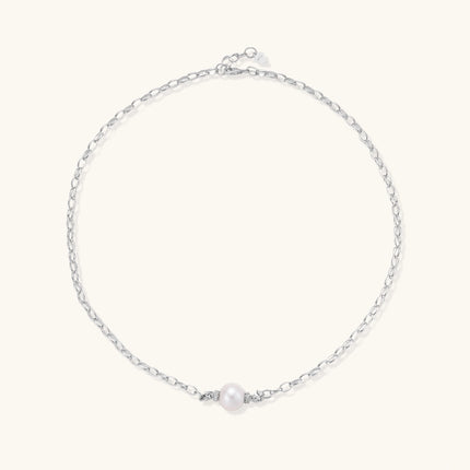Dainty rhodium-plated silver chain necklace with centered 10mm freshwater pearl and crystal accents on cream background