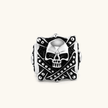 Silver-tone 316L stainless steel skull ring with crossbones, black enamel fill, studded details, and wide shank, 21mm top width.