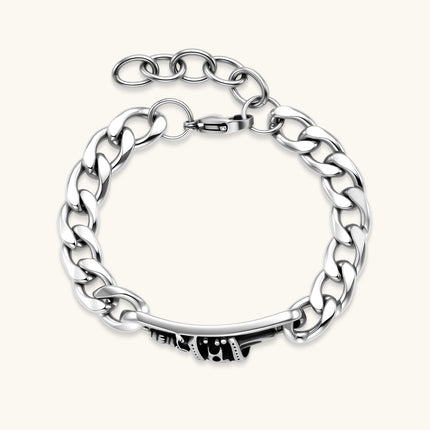 Silver 316L stainless steel Cuban chain bracelet with blackened skull and crown ID bar centerpiece, lobster clasp closure.