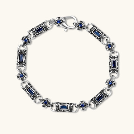 Oxidized silver stainless steel link bracelet with baguette blue CZ stones and intricate scroll engravings, lobster clasp.