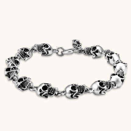 Silver stainless steel bracelet with linked 3D skull charms and a spring-ring clasp, oxidized black detailing, 225mm length.
